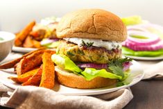 a chicken burger with lettuce and tomato wedges on a plate next to some fries