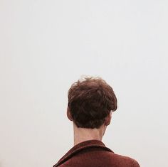 a man standing in front of a white wall with a kite flying above his head