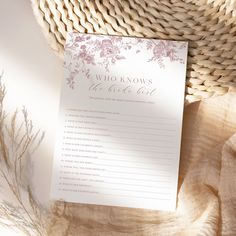 a white and pink wedding stationery with flowers on it sitting next to a wicker basket