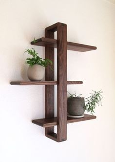 a wooden shelf with two plants on it and one potted plant in the corner