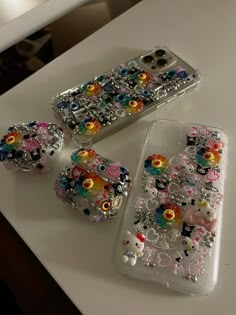 three cell phones are sitting on a table with beaded designs and beads around them