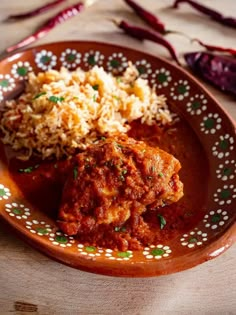 a plate with rice, meat and sauce on it sitting on a table next to other food items