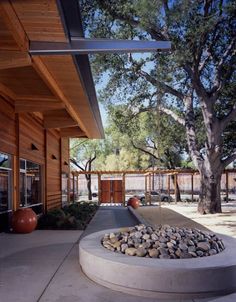 an outside view of a building with trees and rocks in the foreground, near a fire hydrant