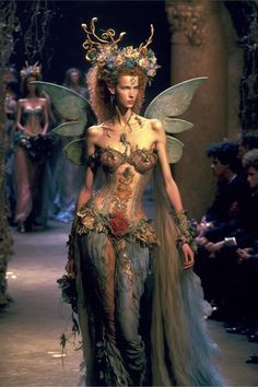 a woman in a corset with wings and flowers on her head is walking down the runway