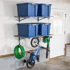 there is a bike hanging on the wall next to two bins and a hose