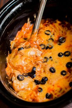 a crock pot filled with black olives and cheese covered chicken in melted cheese