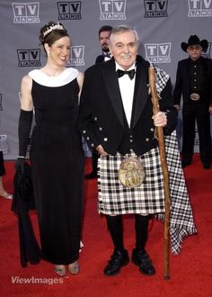 a man in a kilt standing next to a woman wearing a black and white dress