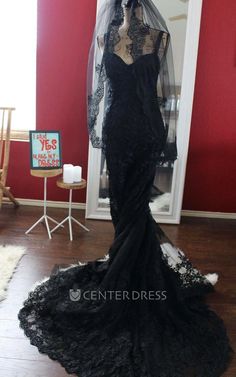 a mannequin wearing a black dress and veil in front of a red wall