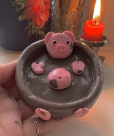 a person holding a small pig in a bowl shaped like a pot with pigs inside