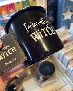 a person holding up a black cup with the words i'm pretty witch on it