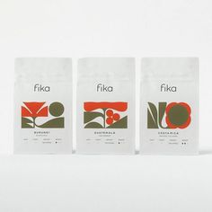 three bags of coffee sitting next to each other on a white surface with red and green designs