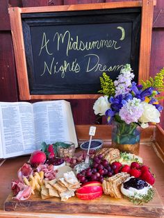 a wooden table topped with lots of different types of food next to an open book