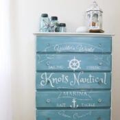 a blue dresser with an anchor painted on the front and bottom, sitting next to a white wall