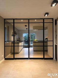 an empty room with glass doors leading into the kitchen