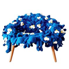 a blue and white pom pom chair with flowers on the bottom, sitting in front of a white background