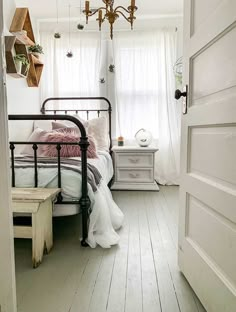 a bed room with a neatly made bed and a chandelier hanging from the ceiling