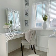 a desk with a mirror, chair and pictures on the wall