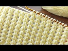 a close up view of a crochet stitch on a knitting machine with yarn in the background