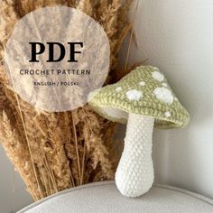 a crocheted mushroom sitting next to some dry grass