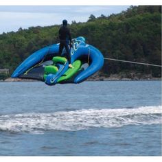 a man riding on the back of a blue and green jet ski while being pulled by a boat