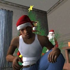 a man wearing a santa hat sitting in front of a christmas tree