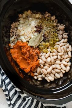 an image of food in the crock pot with beans and seasoning on top