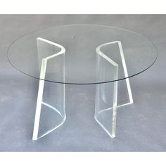 an acrylic table with two curved legs and a glass top on the bottom