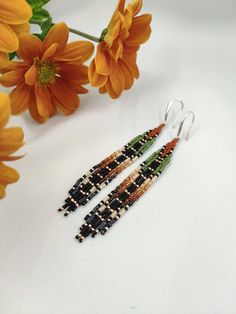 two pairs of beaded earrings sitting next to flowers