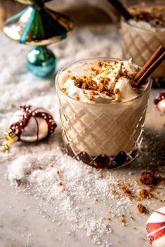 two glasses filled with hot chocolate and marshmallows on top of snow covered ground