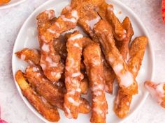 a white plate topped with chicken wings covered in glaze next to two bowls of sauce