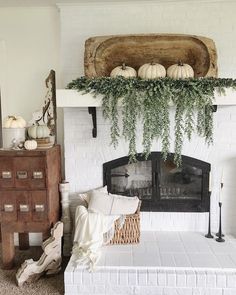 an instagramted photo of a bedroom with white brick fireplace and greenery on the mantel