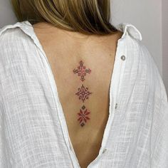 a cross tattoo on the back of a woman's upper back, with red and pink flowers