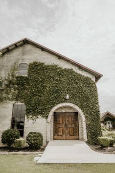 a house covered in vines and ivys with a wooden door on the front entrance