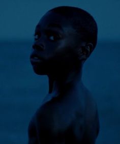 a man standing in front of the ocean at night with his eyes closed and no shirt on