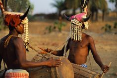 two men with horns and headdress playing drums