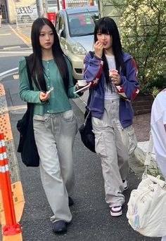 two young women walking down the street talking on their cell phones