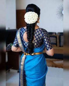 a woman wearing a blue sari with flowers in her hair, looking down at the floor