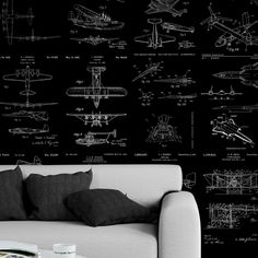 a couch sitting in front of a black wall with blueprint drawings on the walls