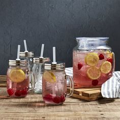 three mason jars filled with lemons and raspberries on top of a wooden table