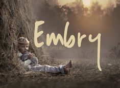 a little boy laying on the ground next to a pile of hay with the words emery written over it