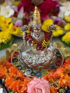 there is a small statue sitting on top of a plate with flowers in the background