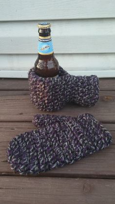 a knitted mitt and beer bottle sitting on a wooden table