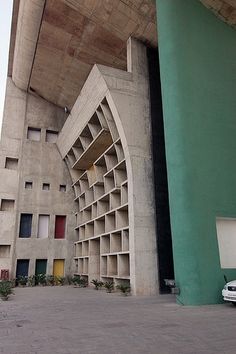 a car parked in front of a building under a bridge with bookshelves on it