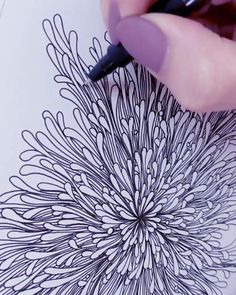 someone is drawing an intricate flower with black marker pen on paper and it looks like they're doing something right now