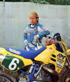 a man standing next to a yellow and blue dirt bike