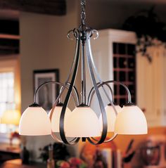 a chandelier with five lights hanging from it's sides in a kitchen