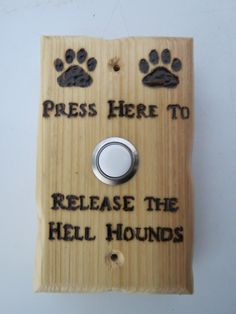 there is a wooden sign that says press here to release the hell hounds with paw prints