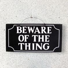 a black and white sign that says beware of the thing hanging on a wall