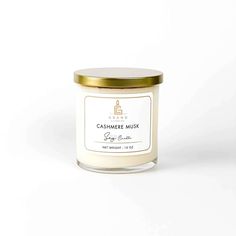 a white candle with gold lid on a white background, the candle has a label that says cashmere musk