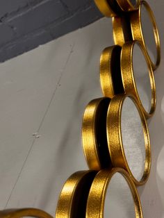 a close up of a metal object on a white surface with some gold rings hanging from it